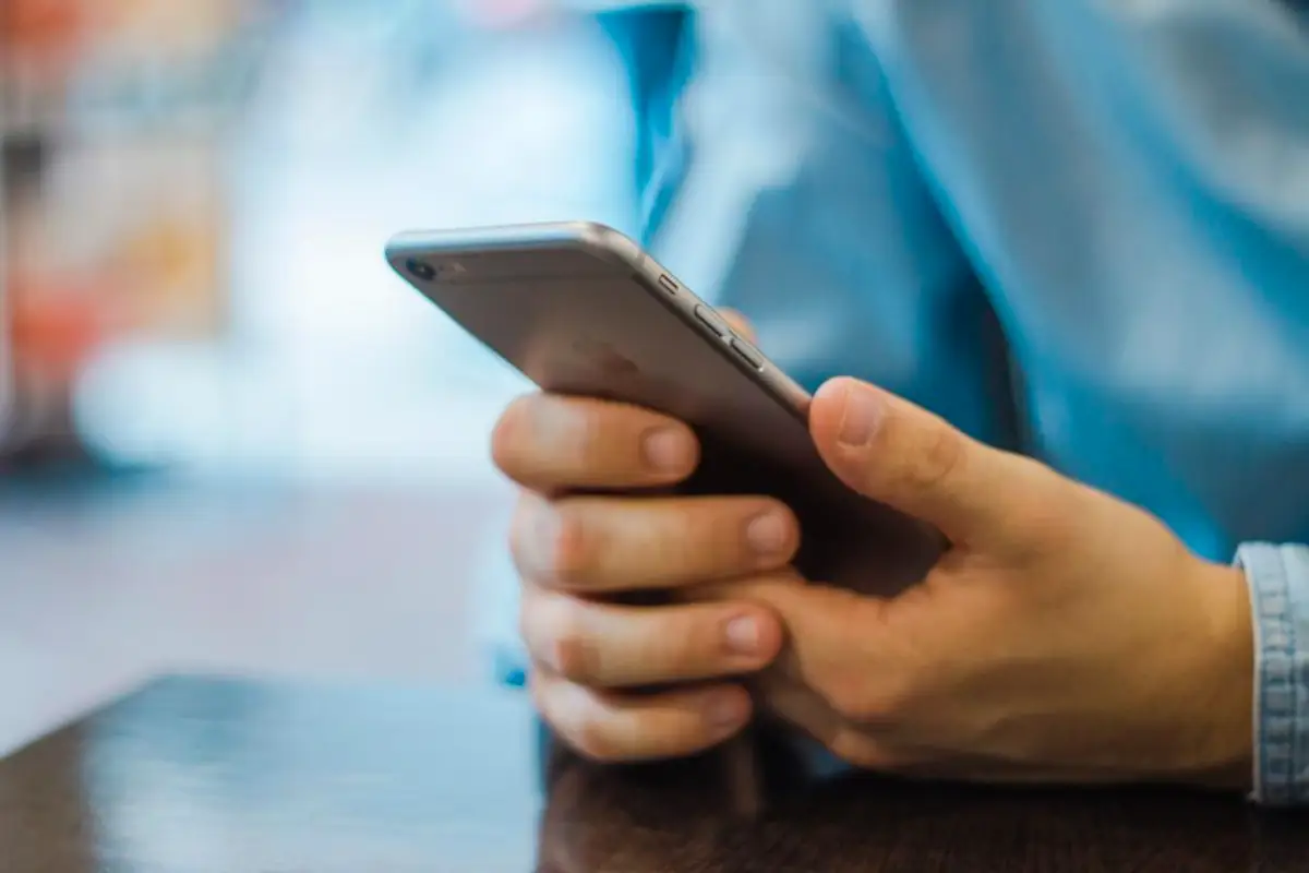 Smartphone tenu en main servant de télécommande pour diffuser une chaîne sur le téléviseur